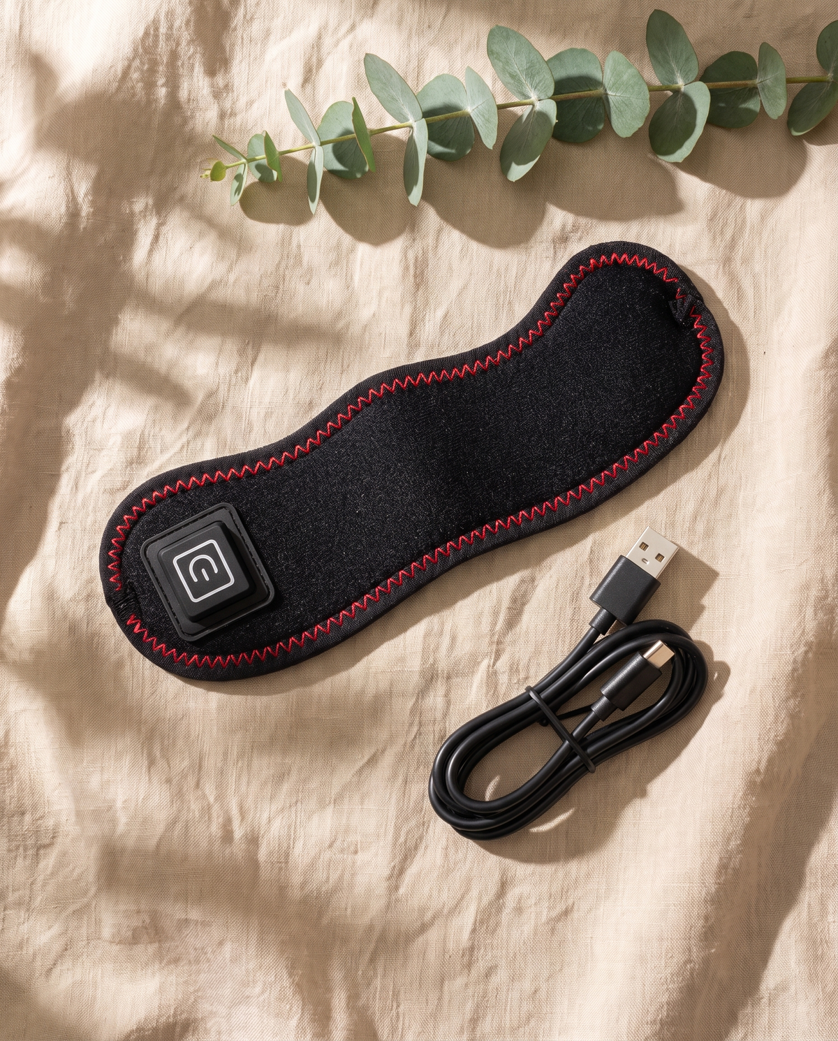 The Sinuglow wrap flat on linen with its USB C cable