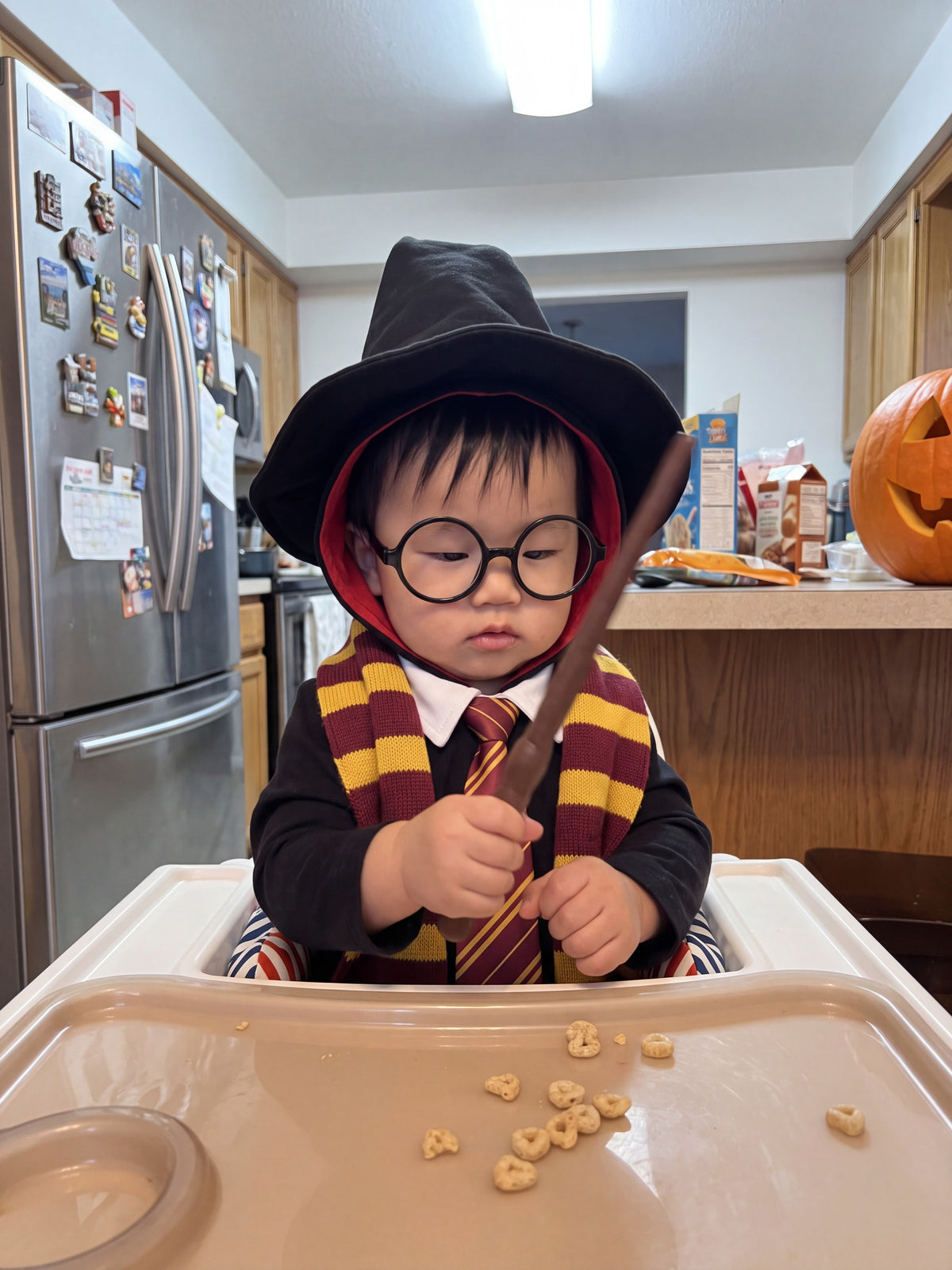 A baby wizard with a wand in his high chair